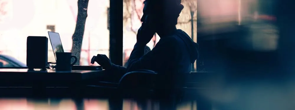 Silhouettes of two people talking beside a bright office window.