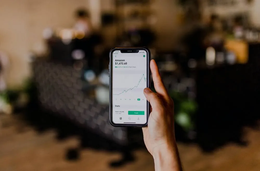 A hand holding a phone showing a line chart.